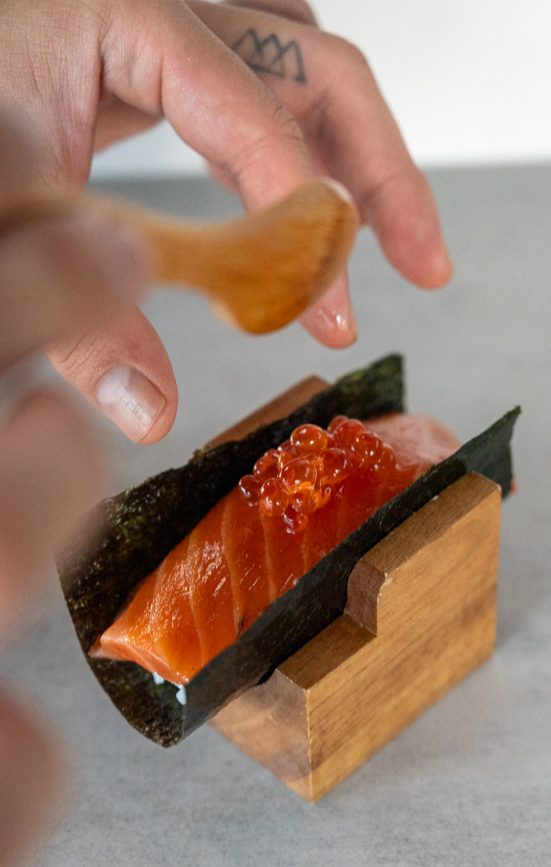 Spooning ikura onto a salmon handroll